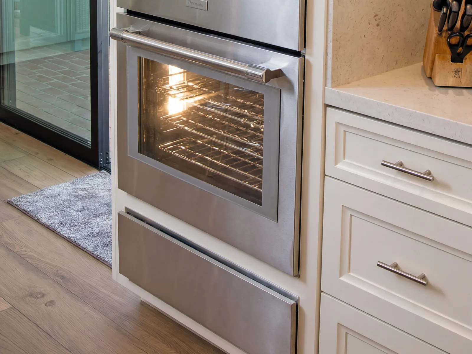 Cajón caliente Thermador en acero inoxidable sin manija, instalado junto a un horno de pared, disponible a través de Artexa México