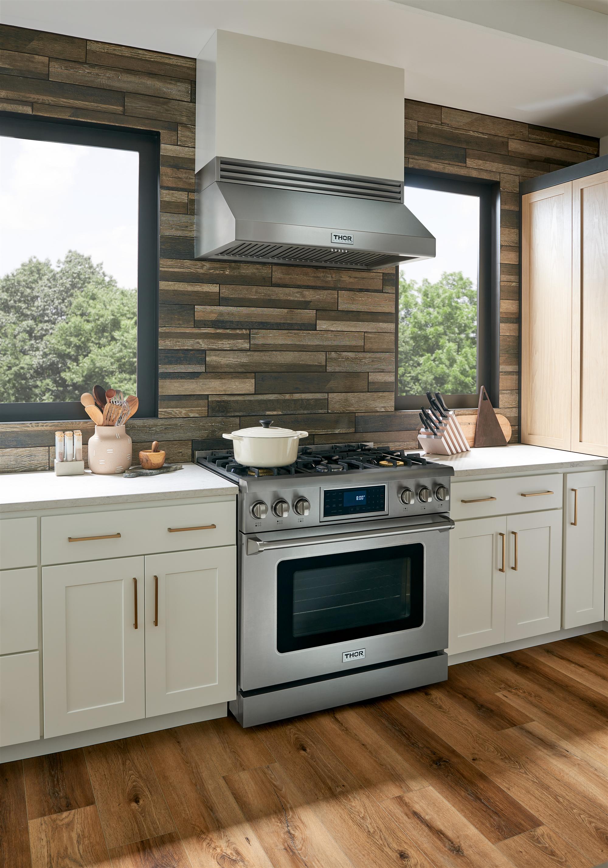 Cocina con estufa de gas Thor Kitchen de 36 pulgadas instalada en pared de madera, con cabinetería blanca — disponible a través de Artexa México