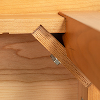 Detailed view of a wooden table showing leg attachment with use of two screws.