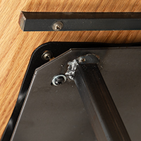 A close up detail of the bottom of a wooden stool that highlights its swivel seat feature.