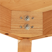 Detailed view of a leg attachment on the underside of a solid wood desk.