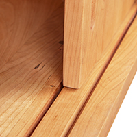 Detailed view of the sliding door construction of a solid wood media console.