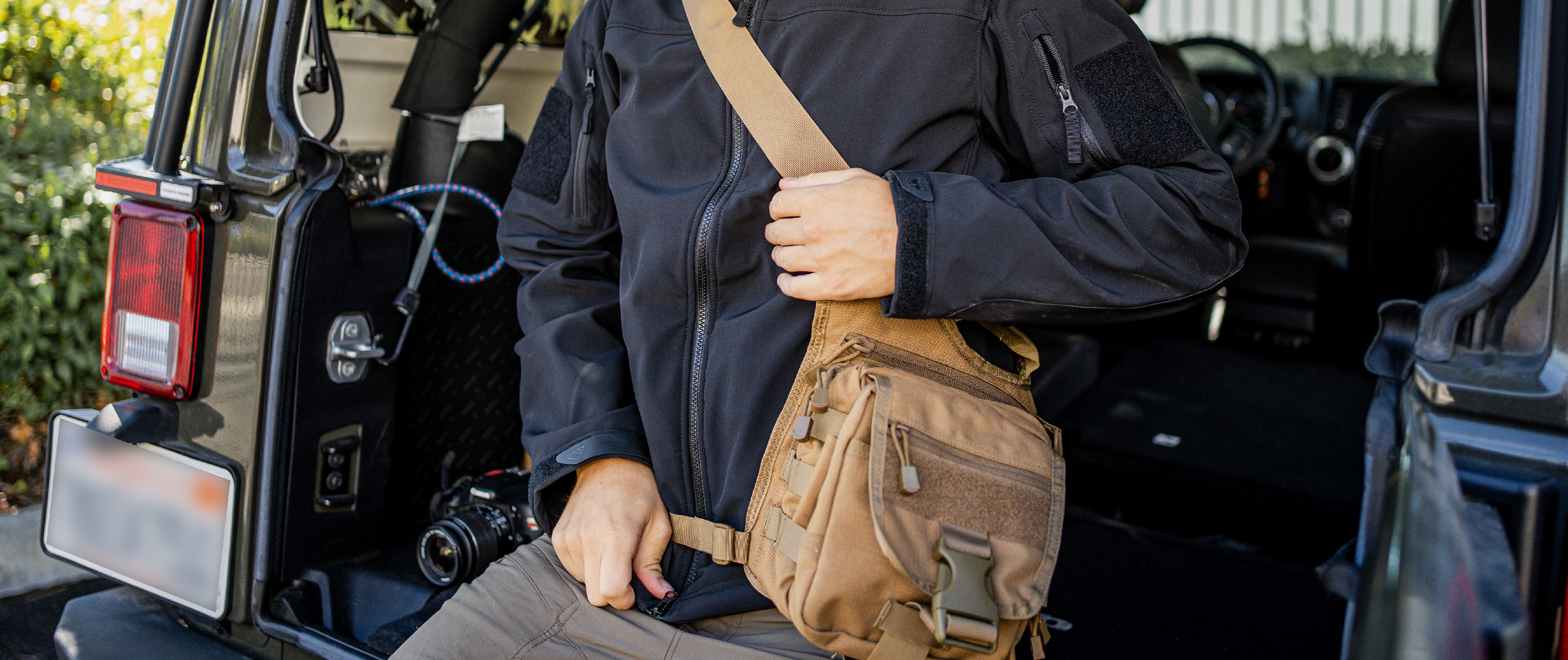 Image of someone sitting on a jeep tailgate wearing the edc bag