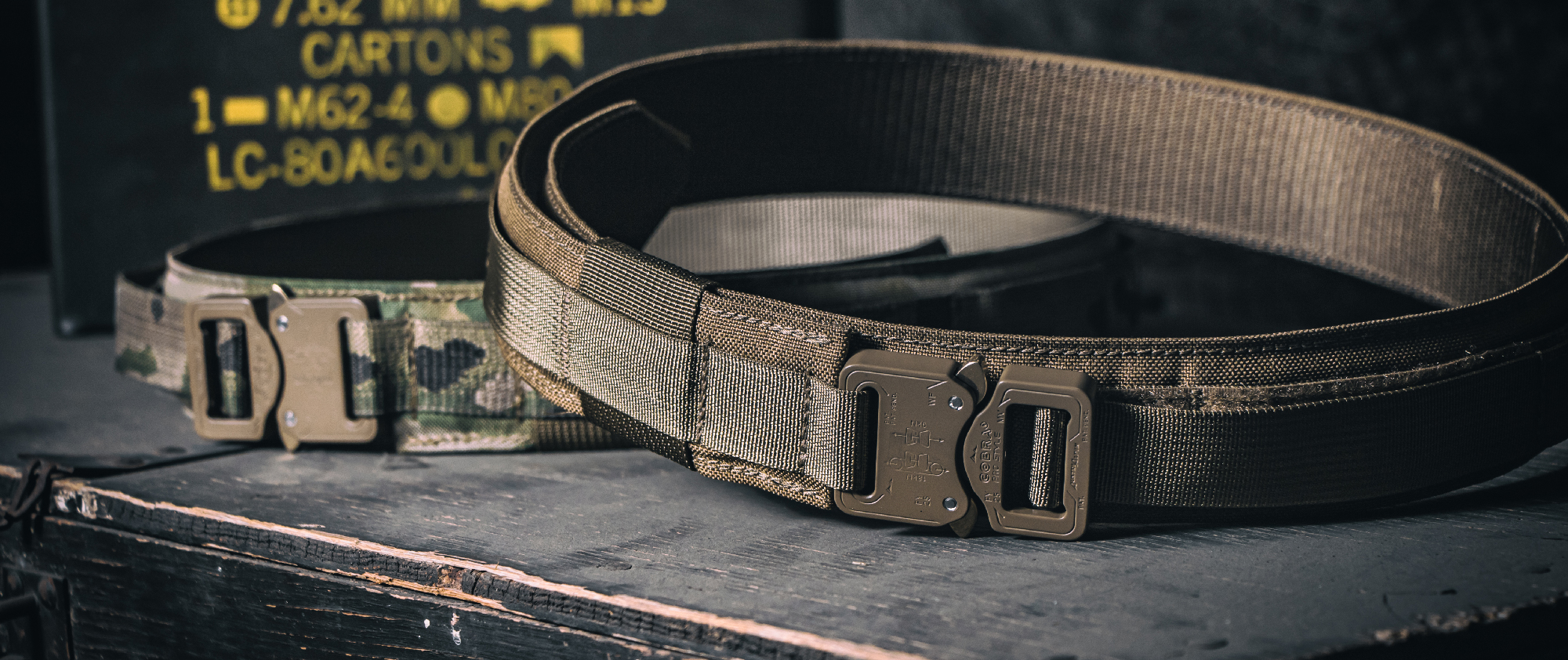 Image of a cobra gun belt next to an ammo can in coyote brown and multicam