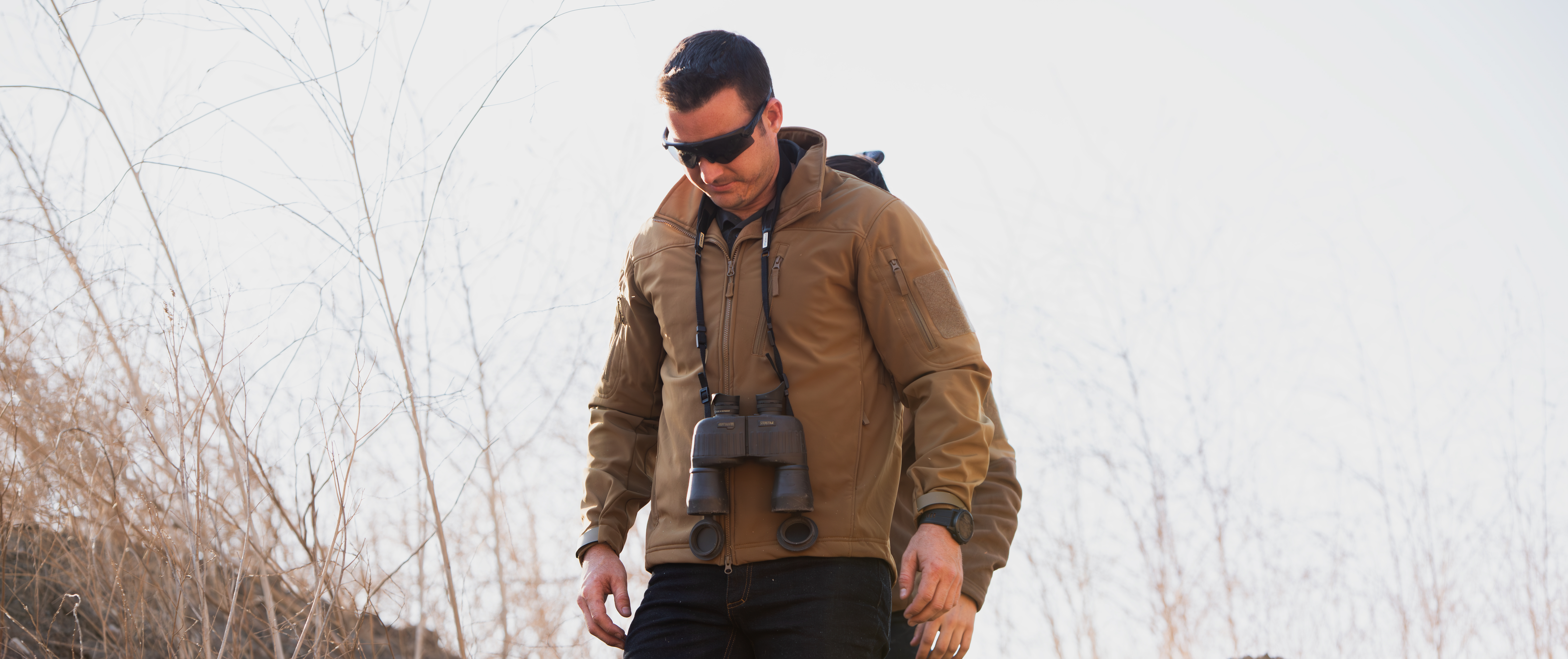 Image of a person in Phantom Softshell Jacket walking with Binoculars