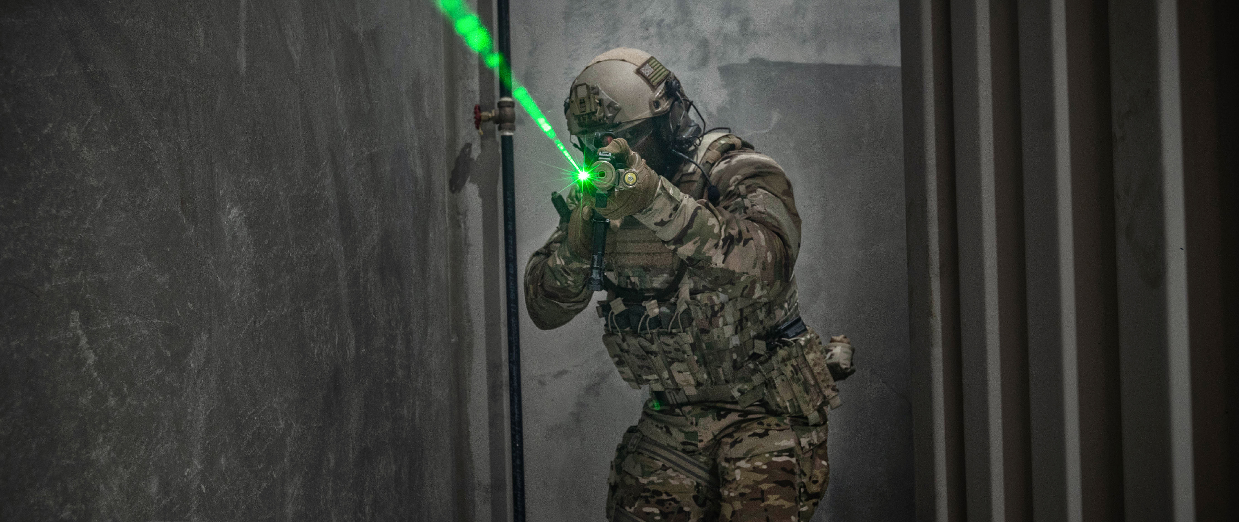 Image of a special operations soldier in the vanquish plate carrier shining a laser.