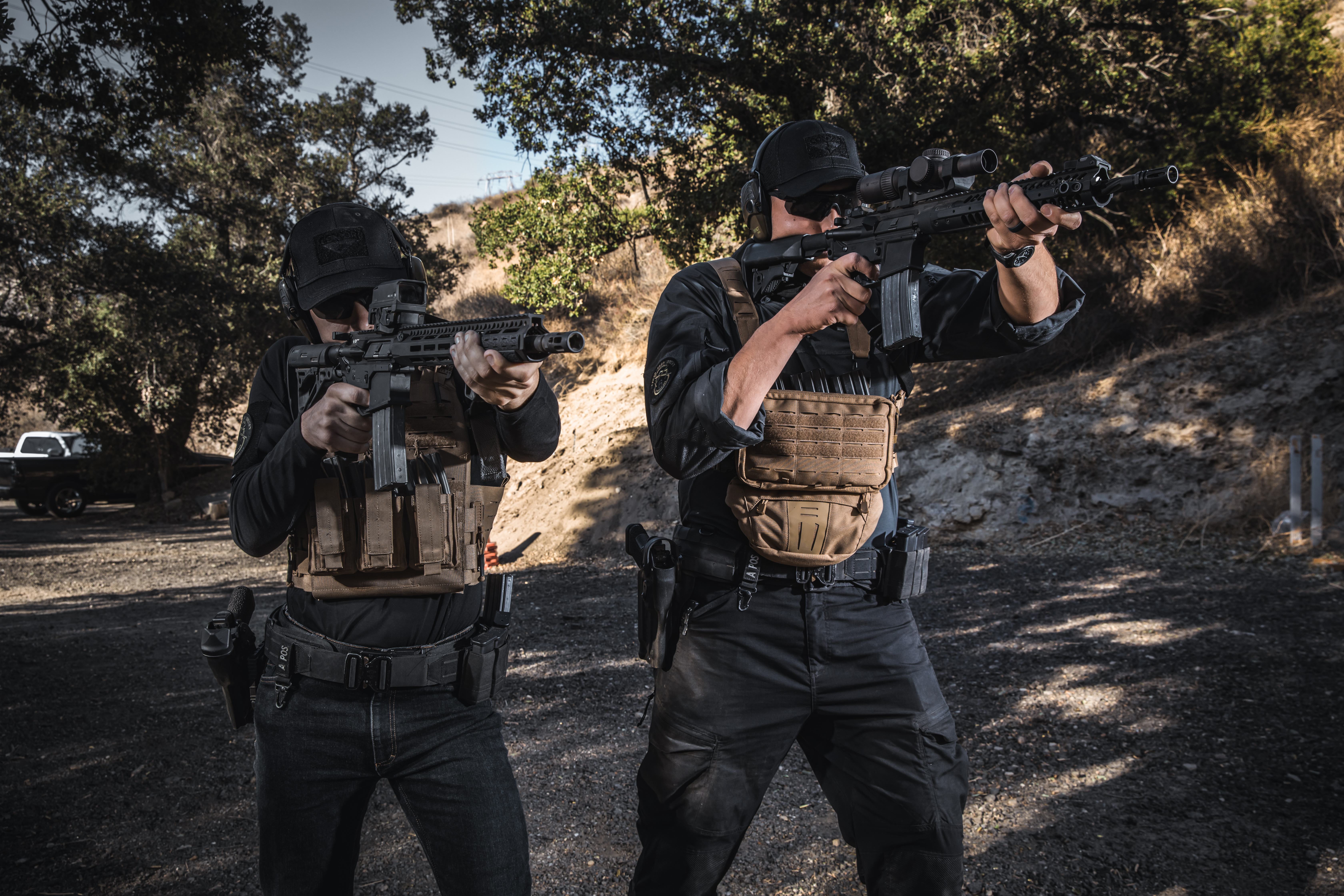 Image of a man holding a rifle wearing a stowaway chest rig with an attached dangler pouch