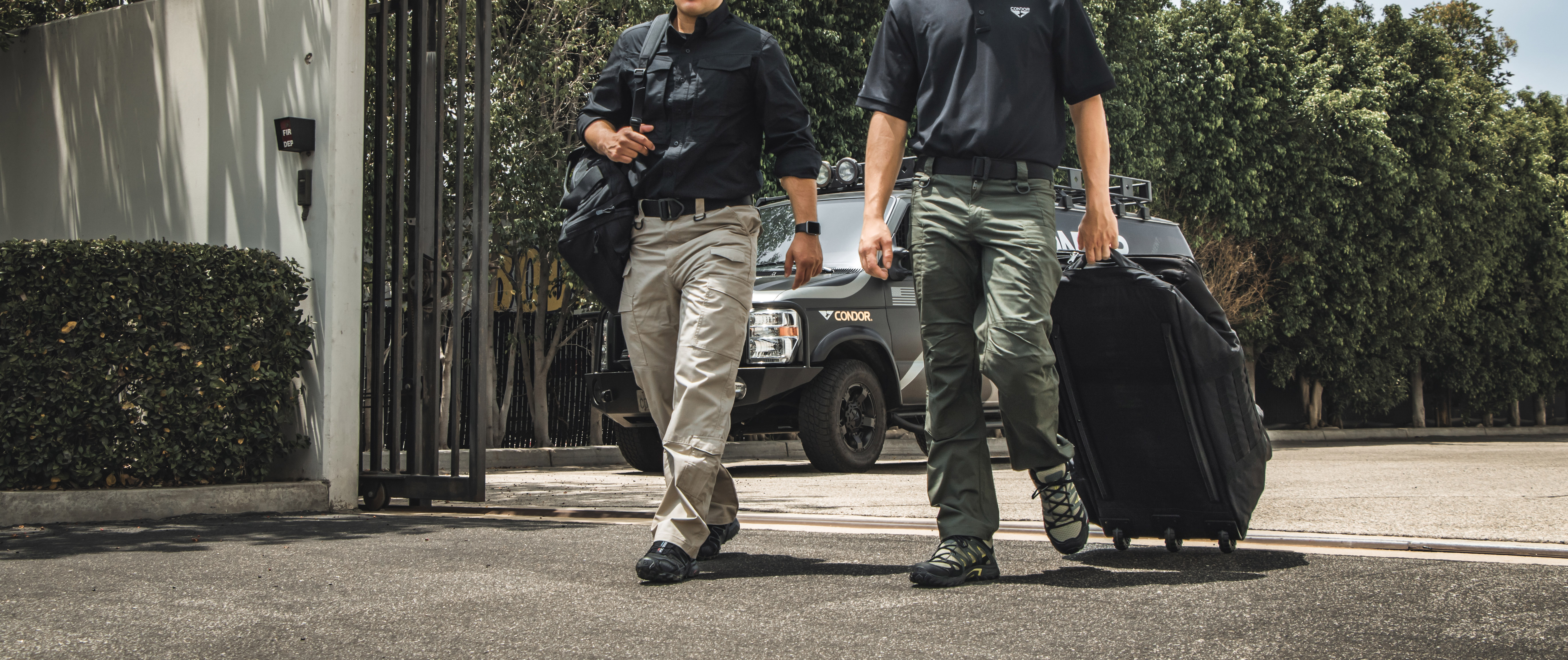 Image of two workers carrying some gear wearing the sentinel pants as a uniform