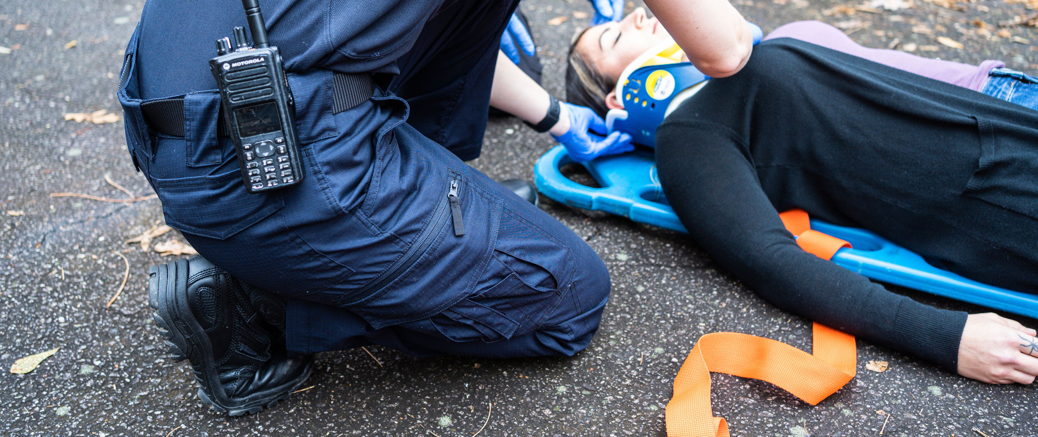 Image of an EMT crouched beside an injured person while wearing the EMS Protector Pants