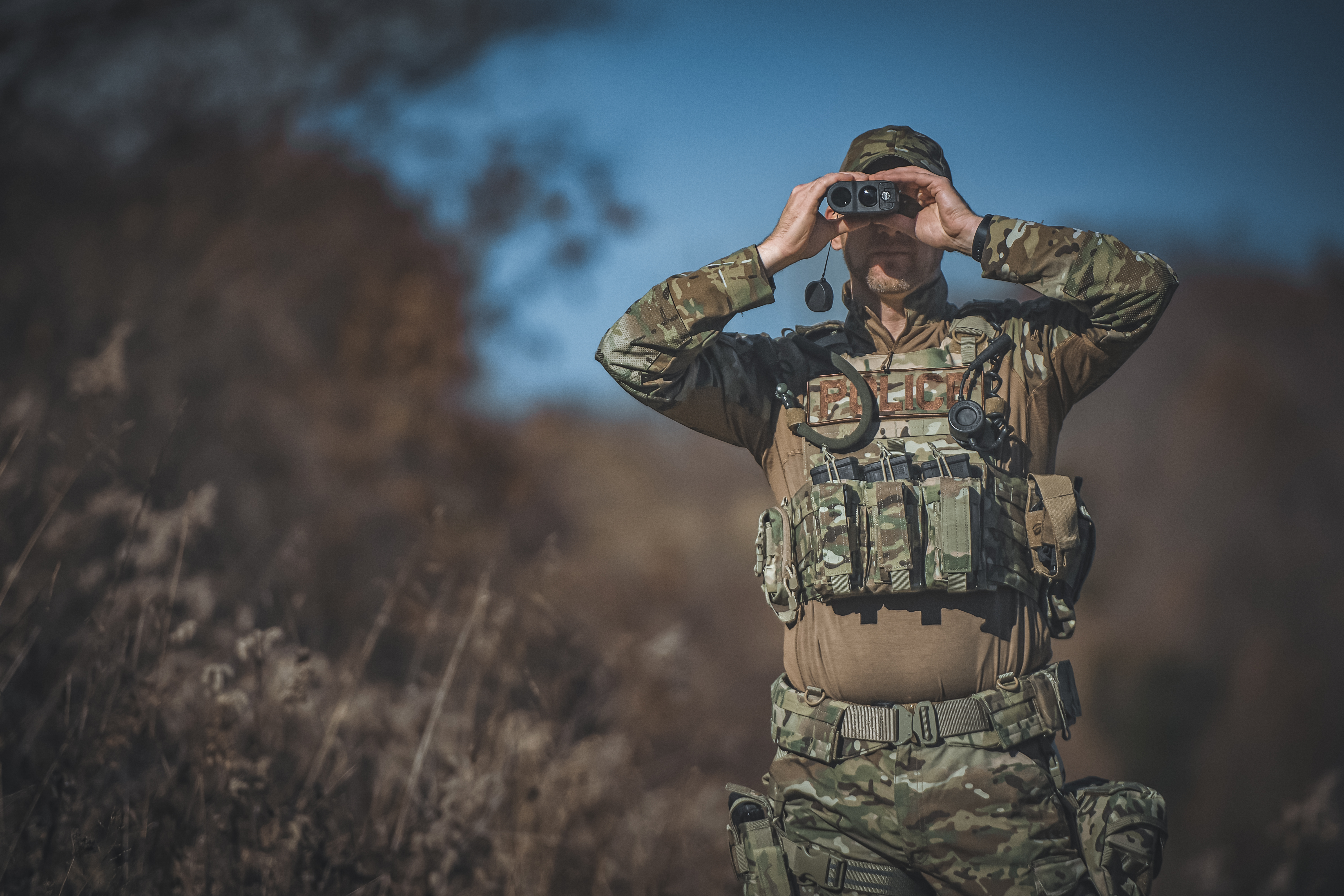 Image of a police sniper using a range finder wearing a triple kangaroo pouch