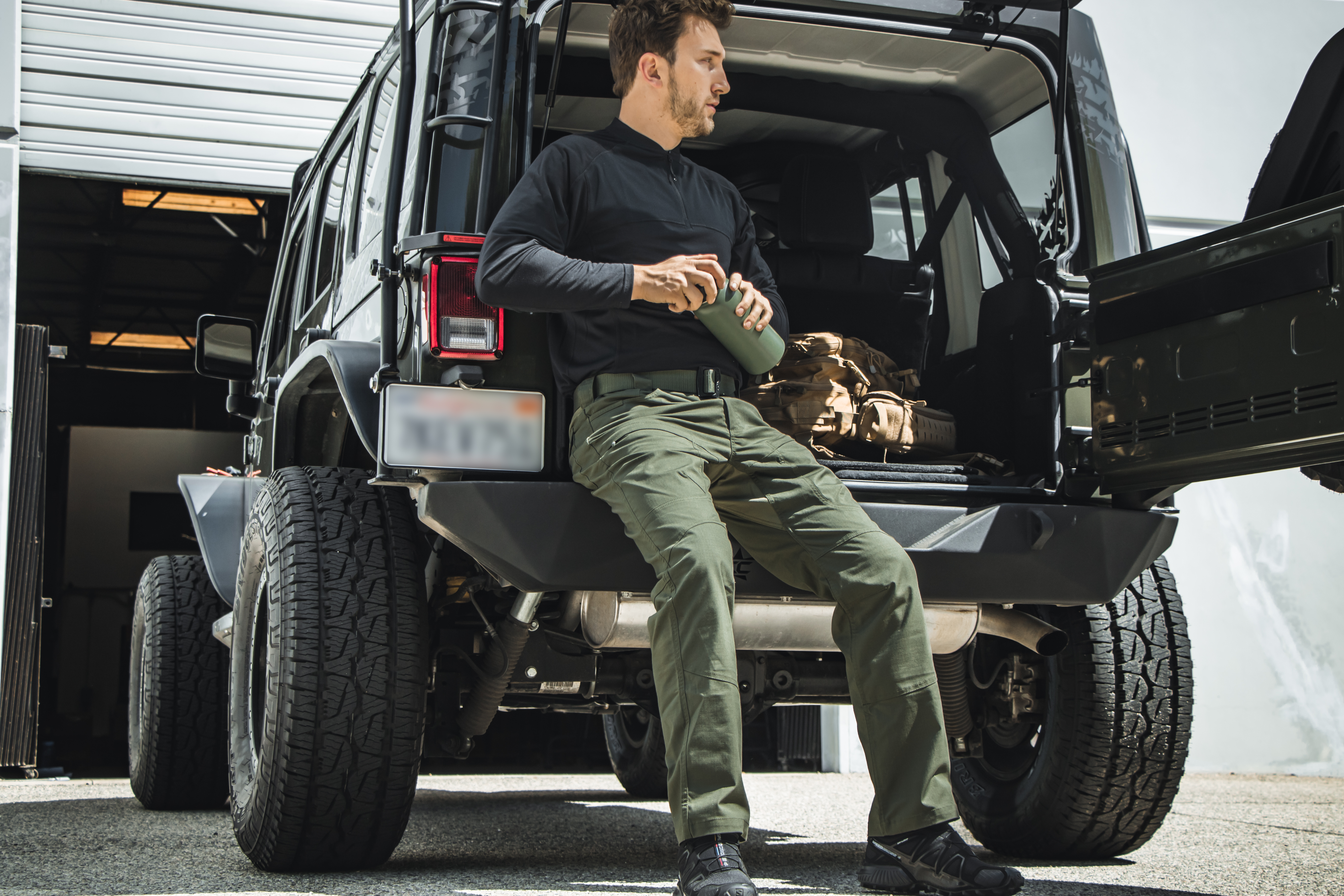Image of a person sitting in the bed of a jeep wearing his odyssey gen II pants