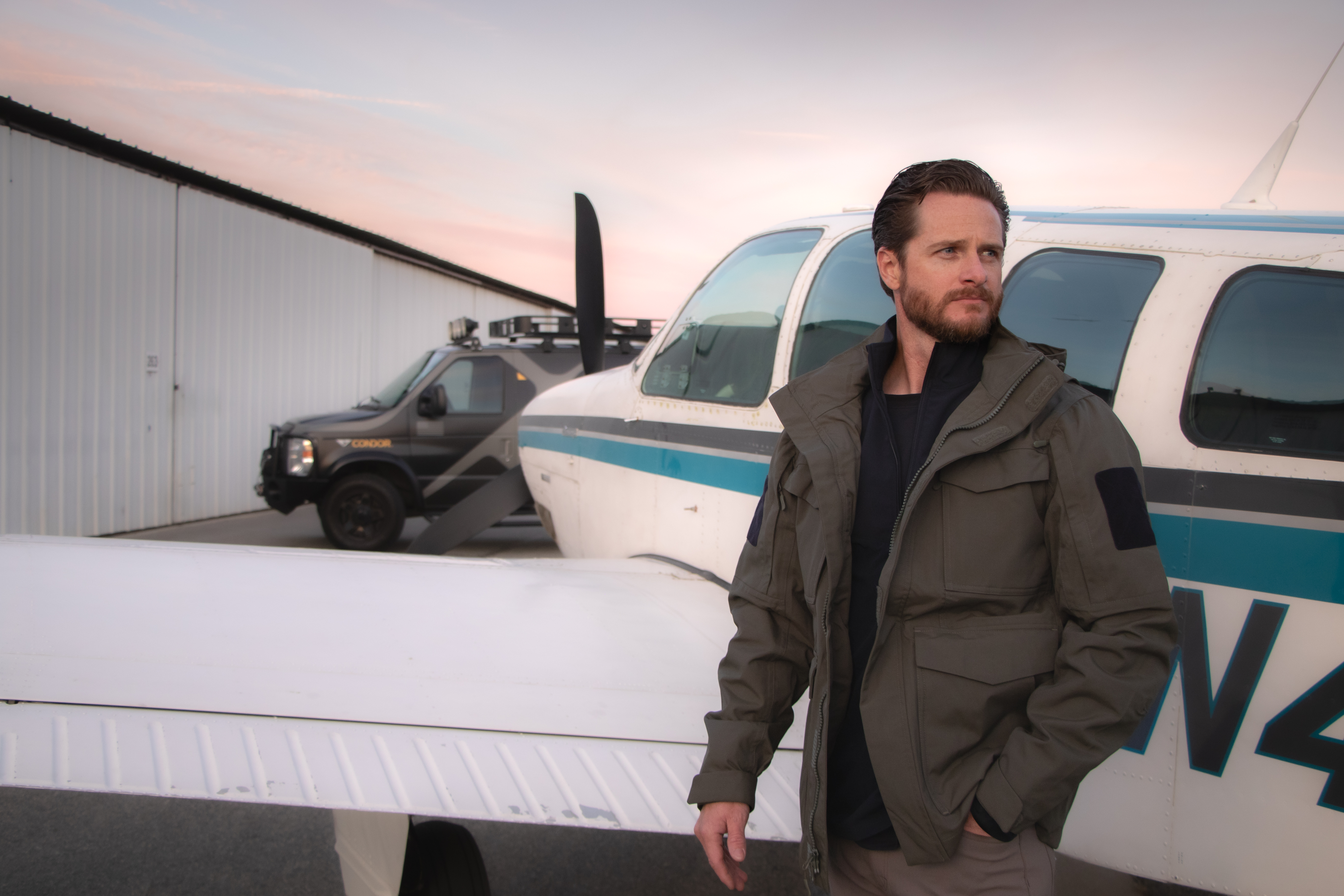 Image of a person standing next to a plane wearing the waterproof parka