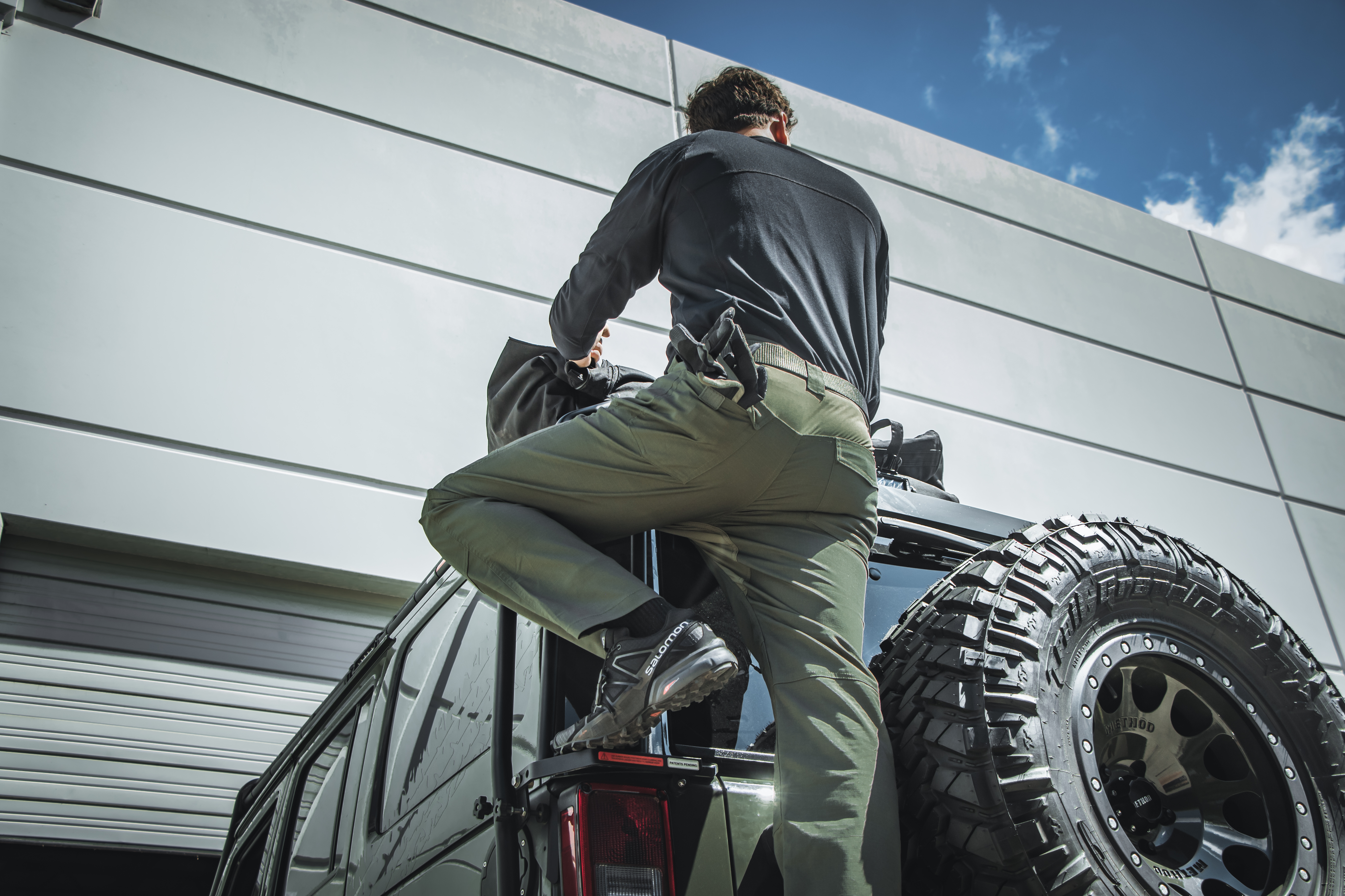 Image showing a person climbing on a jeep while wearing the odyssey pants gen II