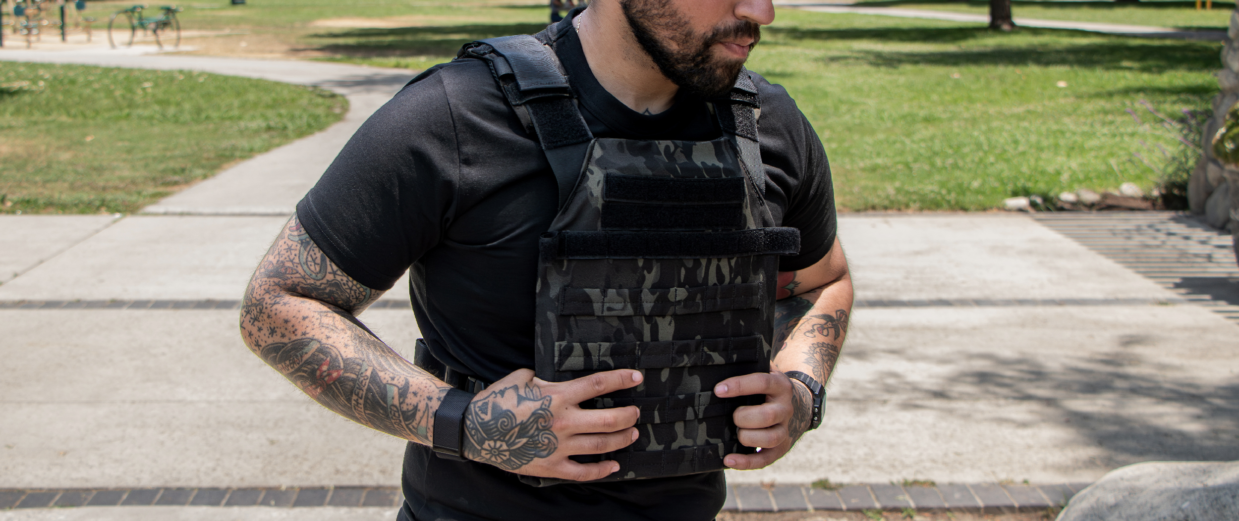 Image of someone at a park taking off a multicam black plate carrier