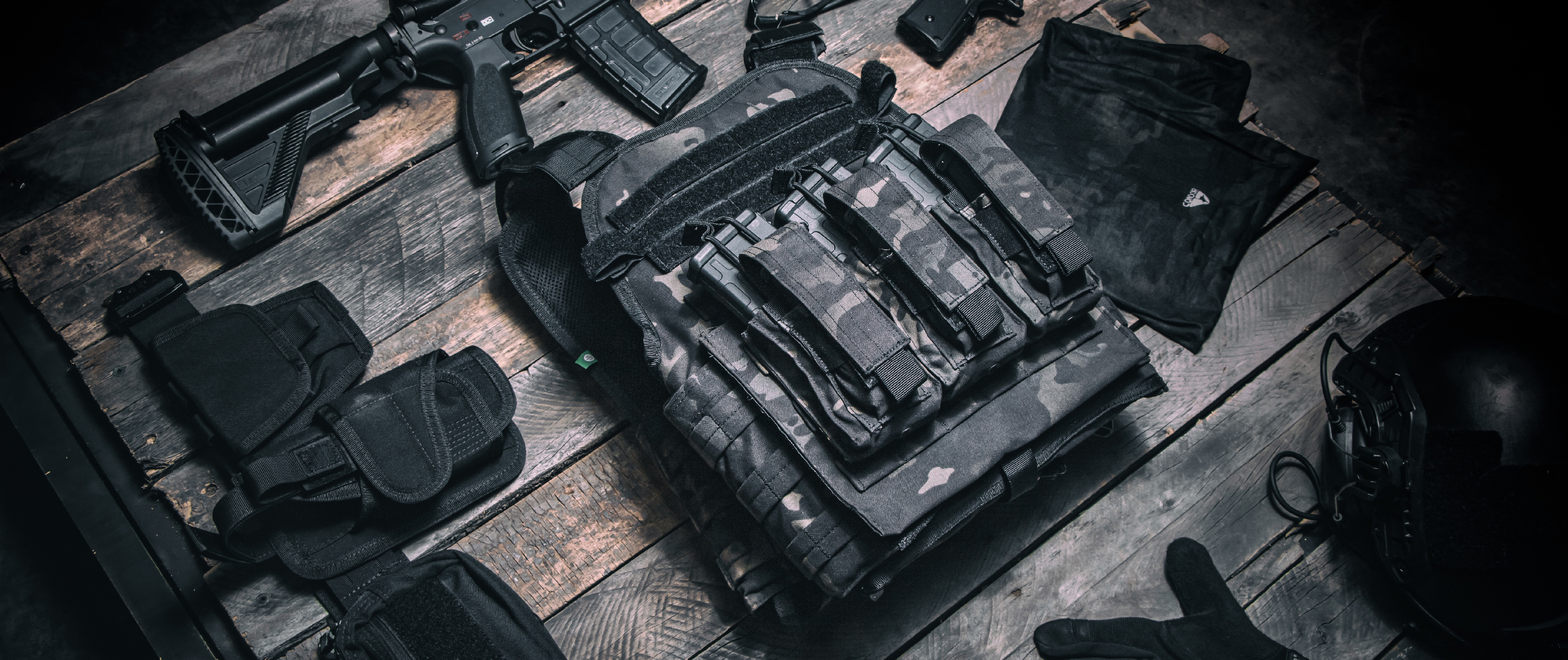 Image showing the multicam black plate carrier on a pallet next to a gun and equiipment