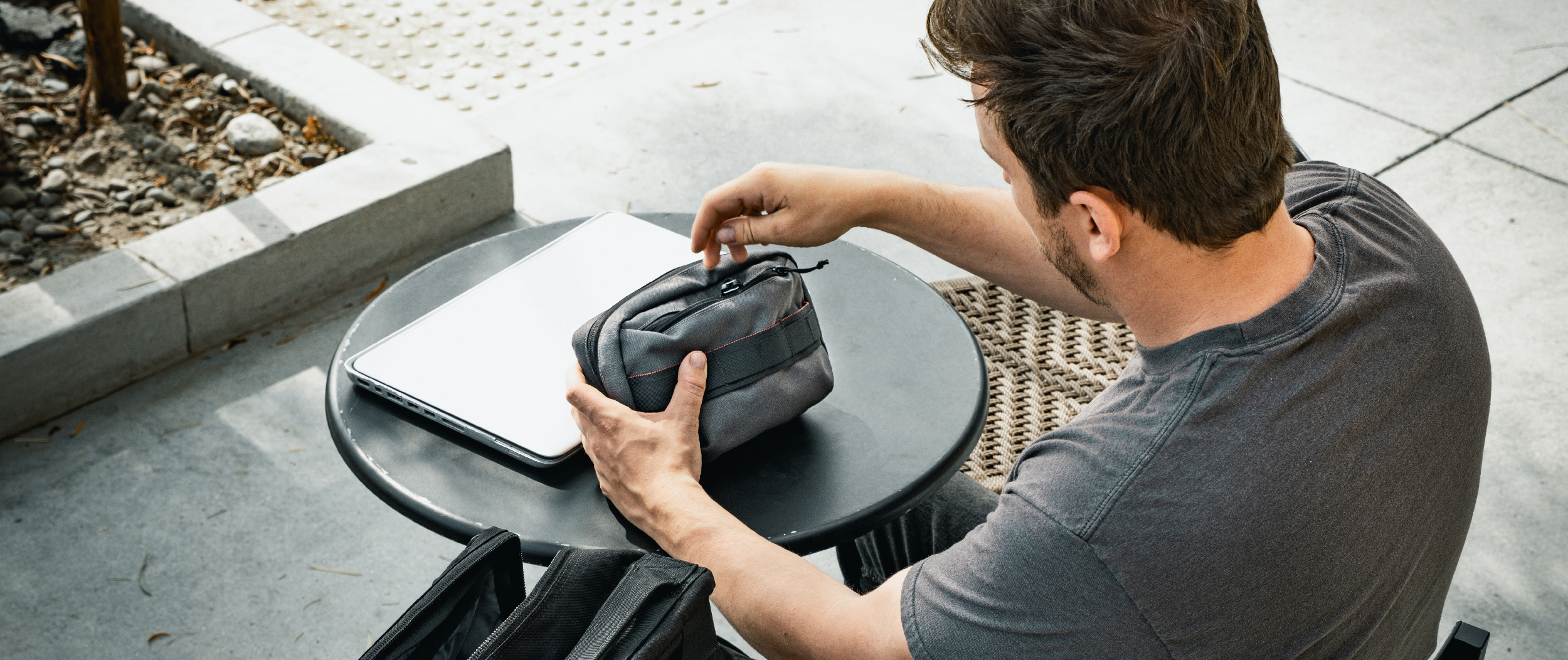 Image of a guy opening his tech pouch at a table
