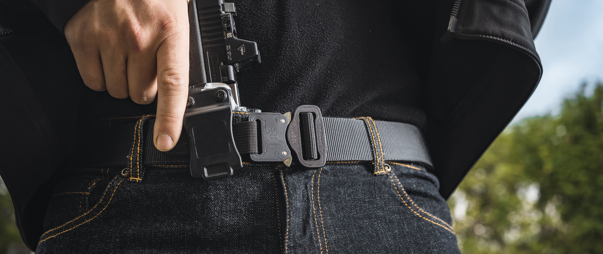 Image of someone drawing from a concealed carry position while using the hybrid edc belt