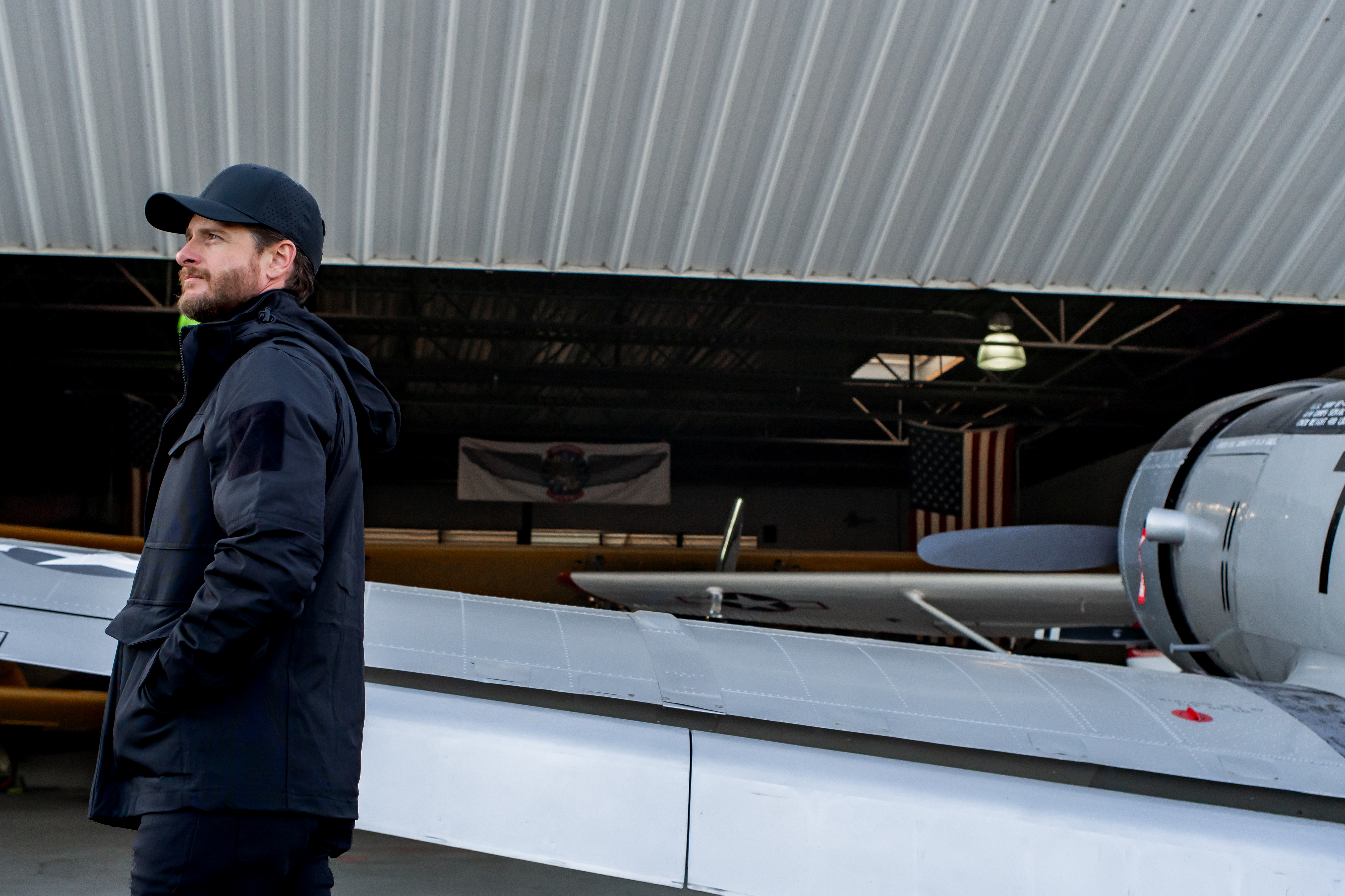 image of a person next to a plane wearing the waterproof parka with the hood up